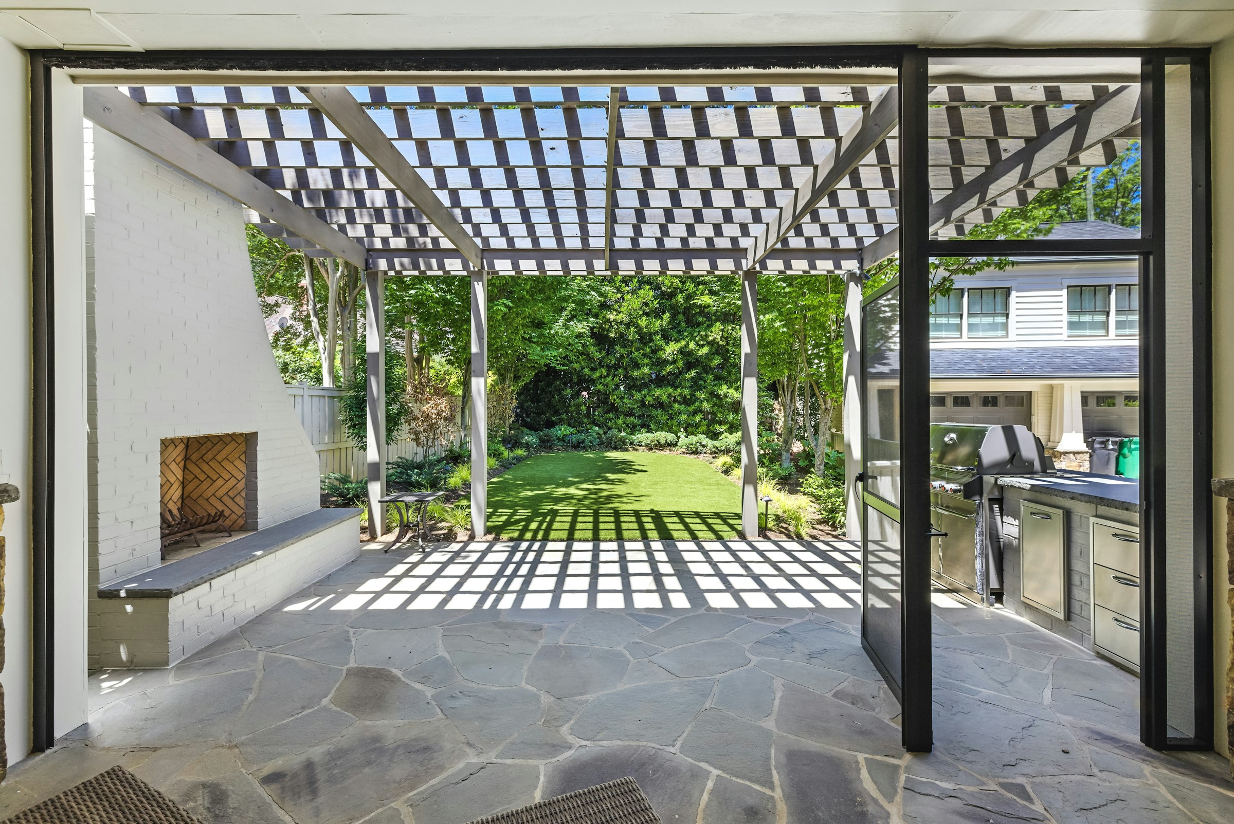 Covered outdoor patio with a pergola, fireplace and outdoor kitchen