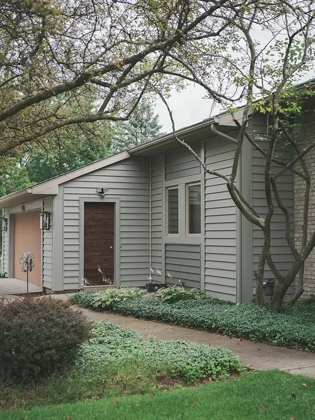 two-story home with aging shingles shown during roof inspection