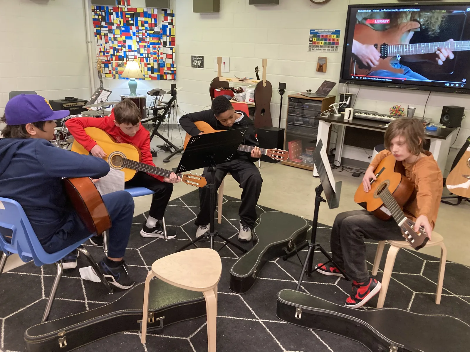 Students practising guitars in the music classroom.