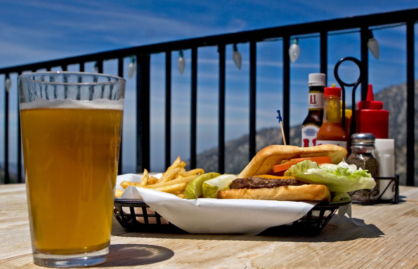 A pint and a burger on the deck rail with the mountains behind