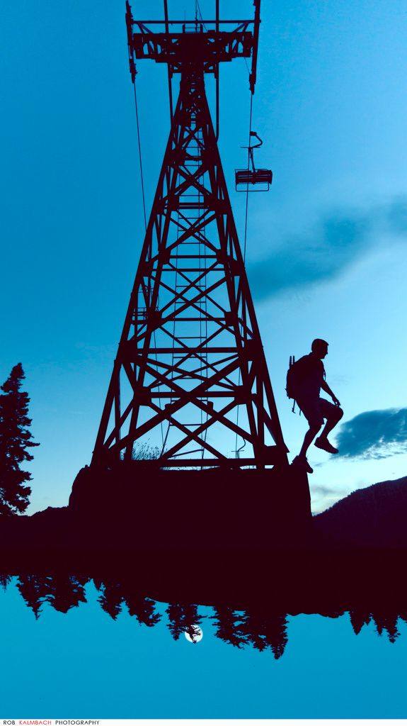 A hiker beside a lift tower at dusk