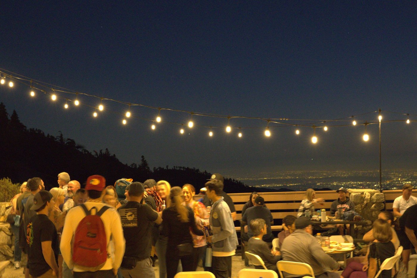 Guests on the deck at night under string lights