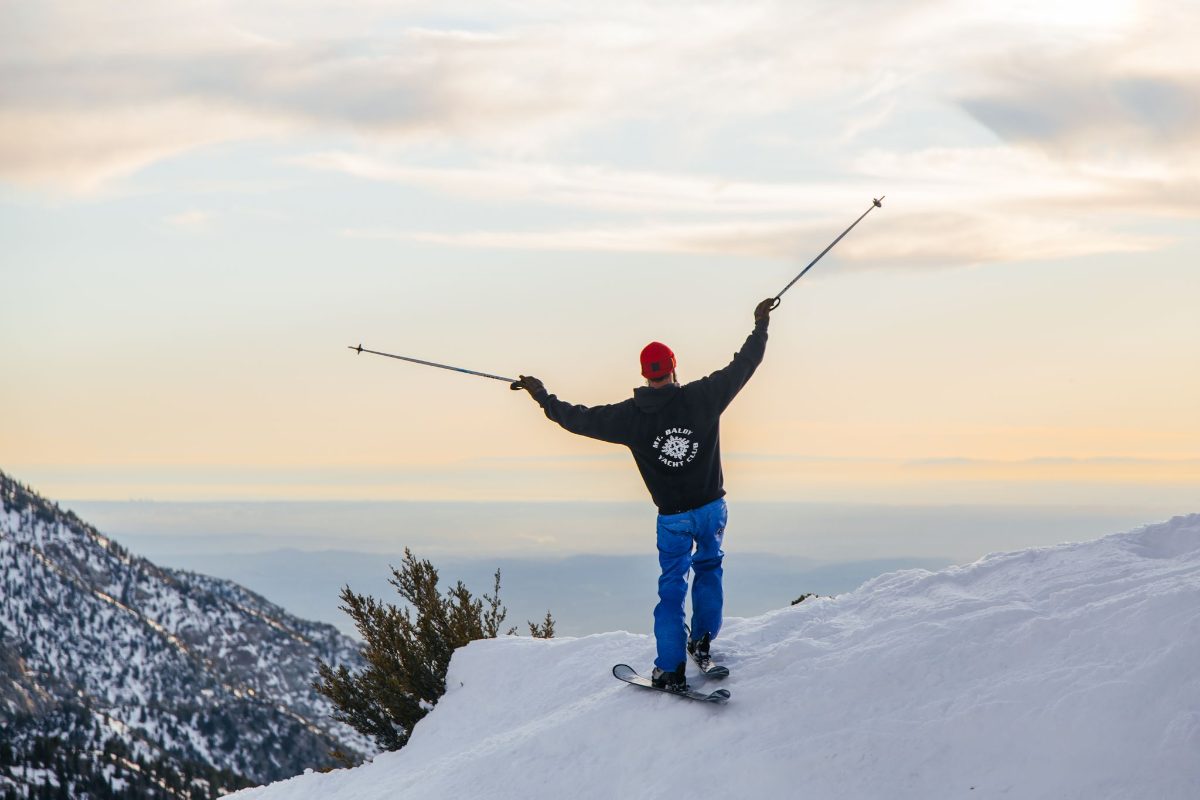 A skier with arms raised above a sea of clouds
