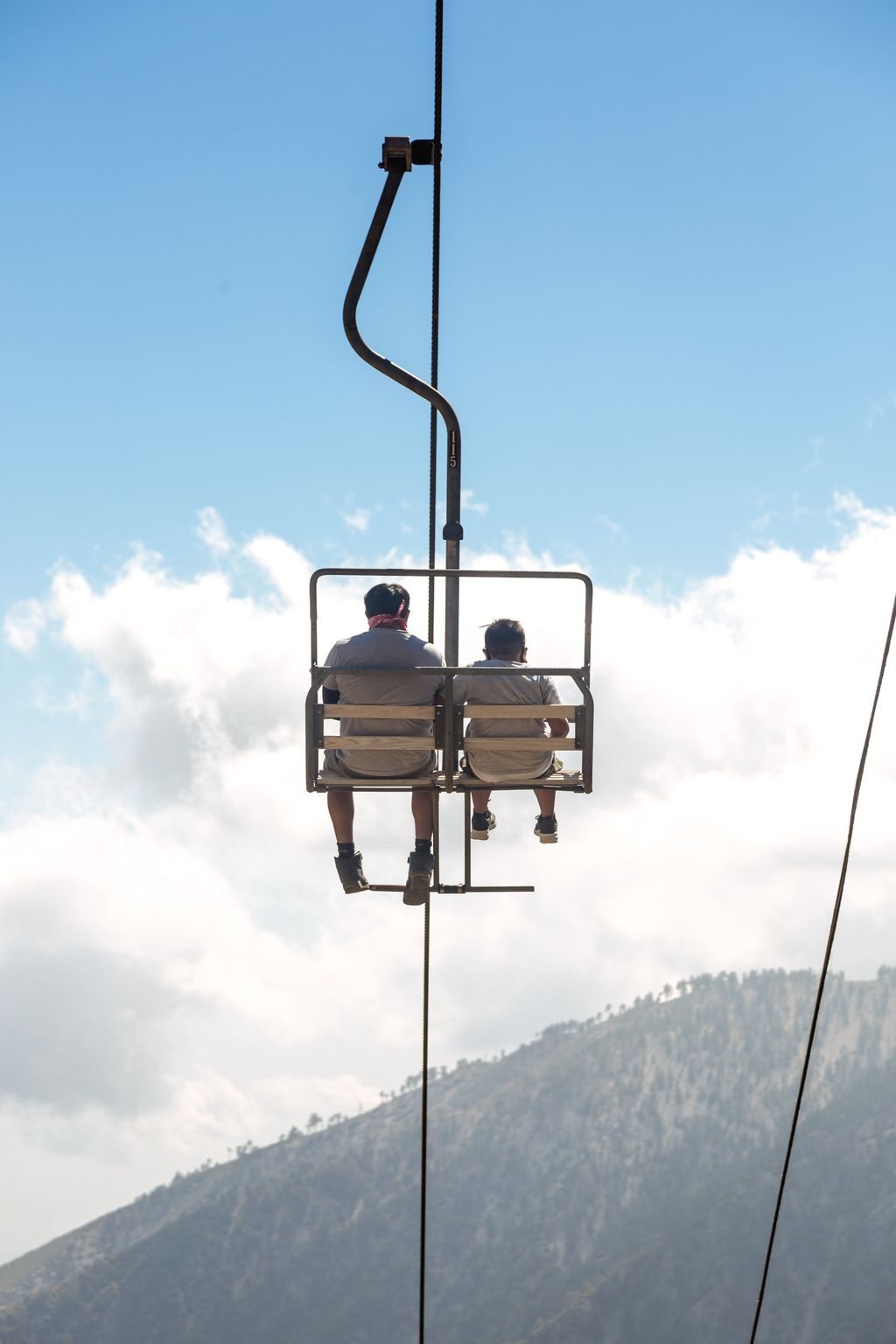 Chairlift riders against summer clouds