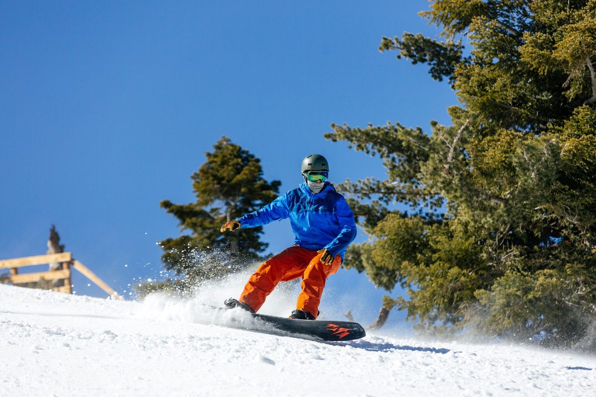 A snowboarder on a sunny groomed run