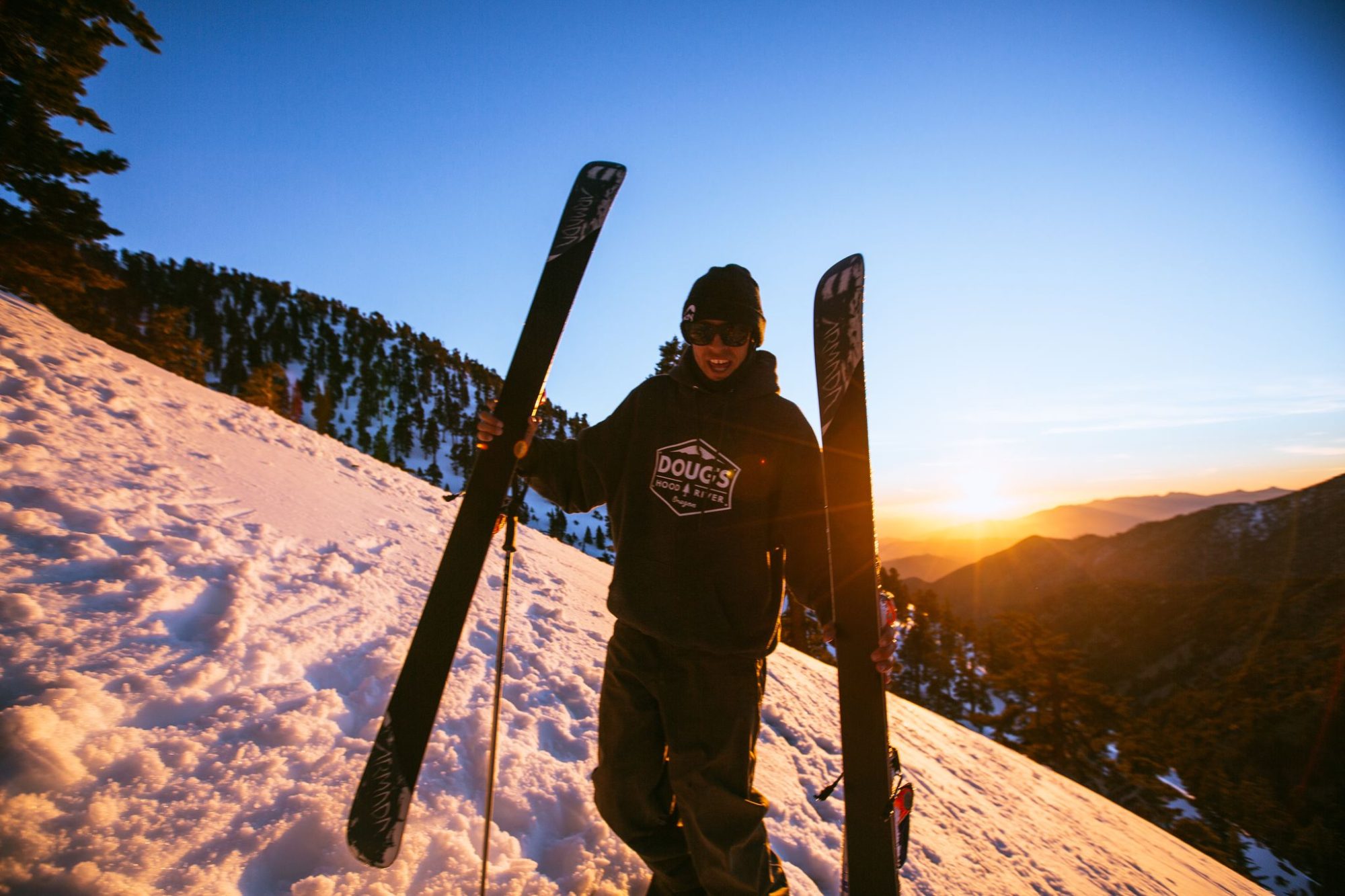 A skier holding skis at sunset on Mt Baldy