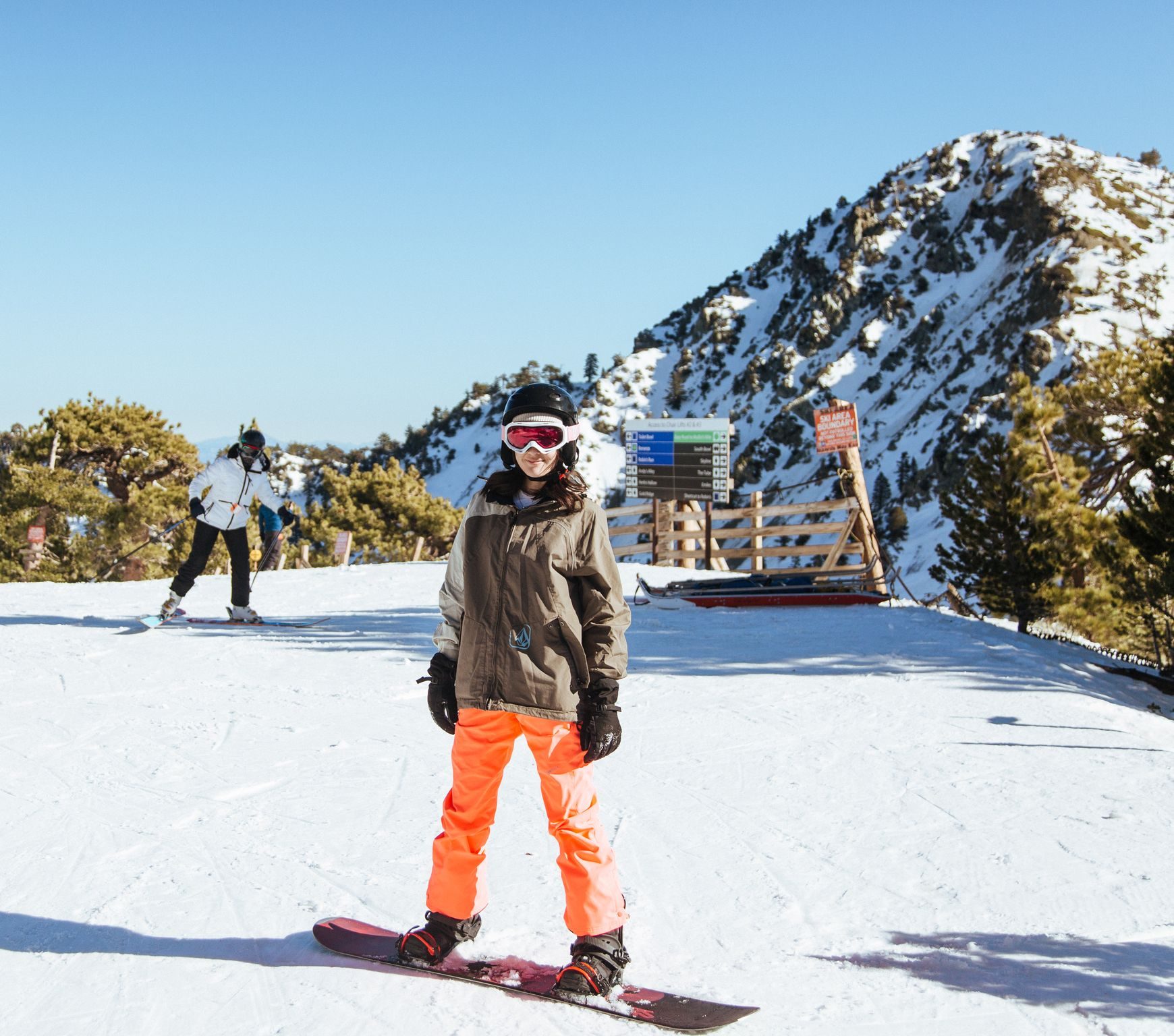 A snowboarder at the base area on a sunny day