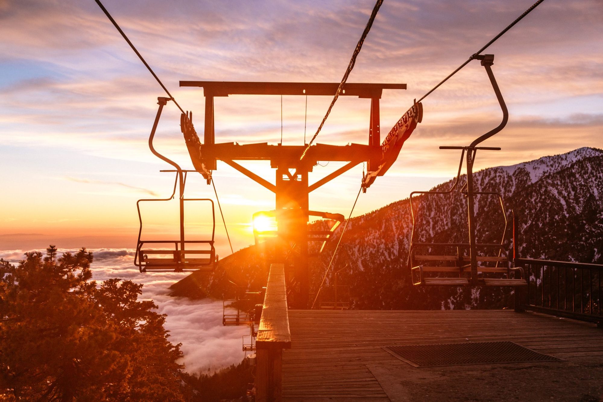 Empty chairs at the lift station at sunset above the clouds