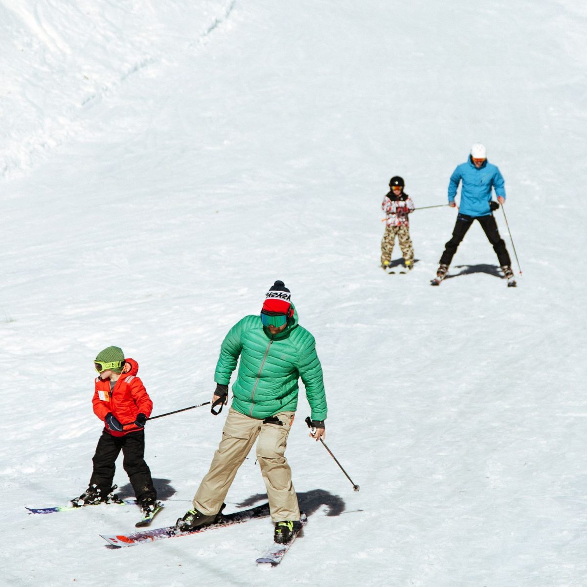 An instructor skiing with kids on the beginner slope