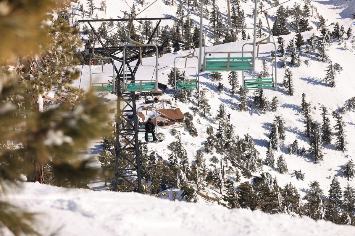 Green chairs riding over snowy pines