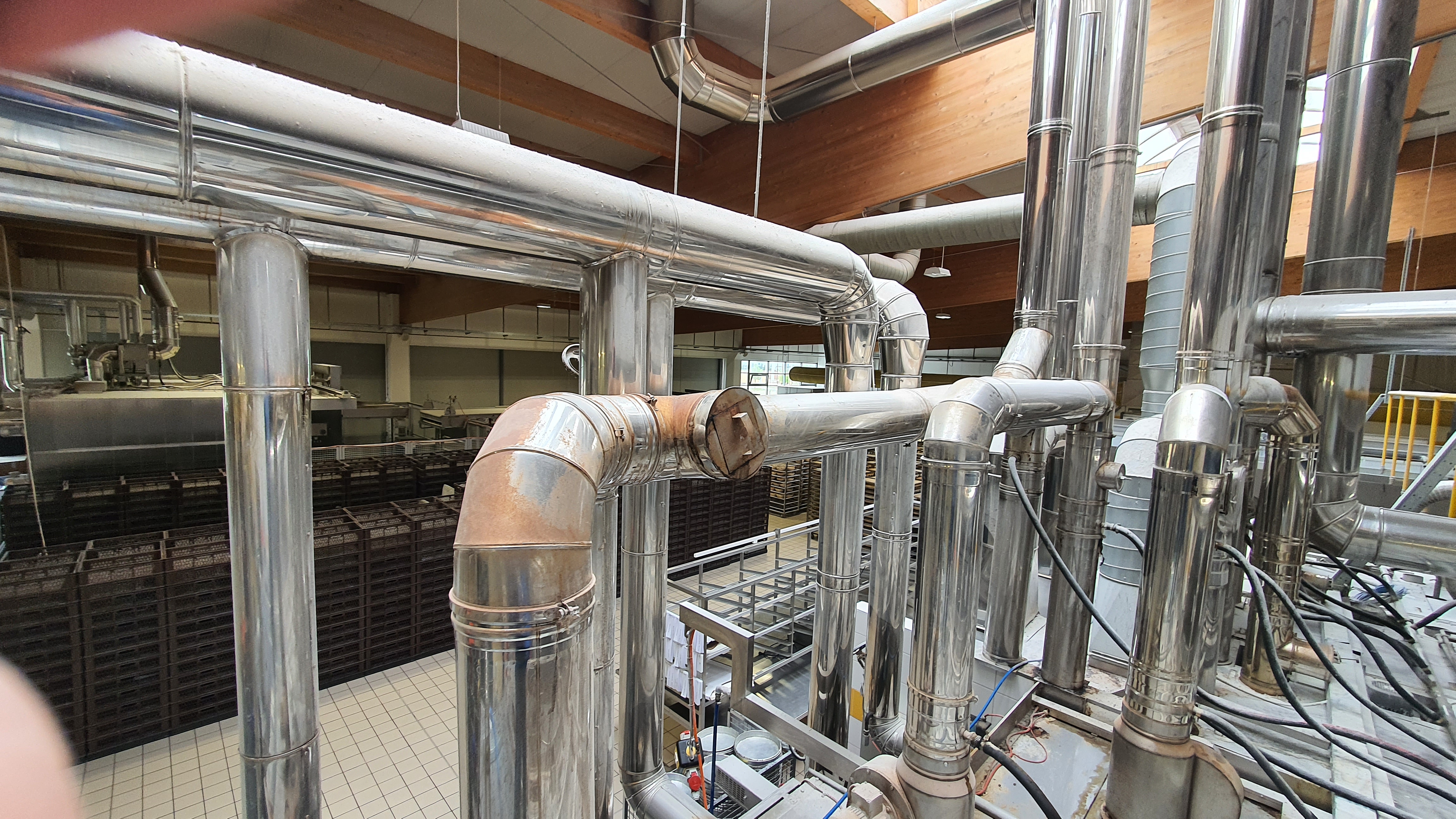 Inox dimovodni sustav s cijevima i ventilacijom u industrijskom objektu.