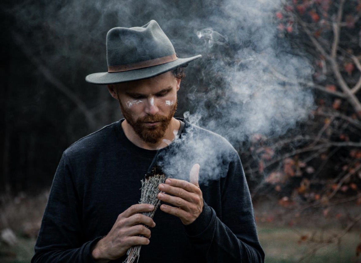 Man sitting alone on rocky outcrop at sunset for reflection and integration