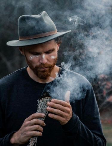 Man sitting alone on rocky outcrop at sunset for reflection and integration