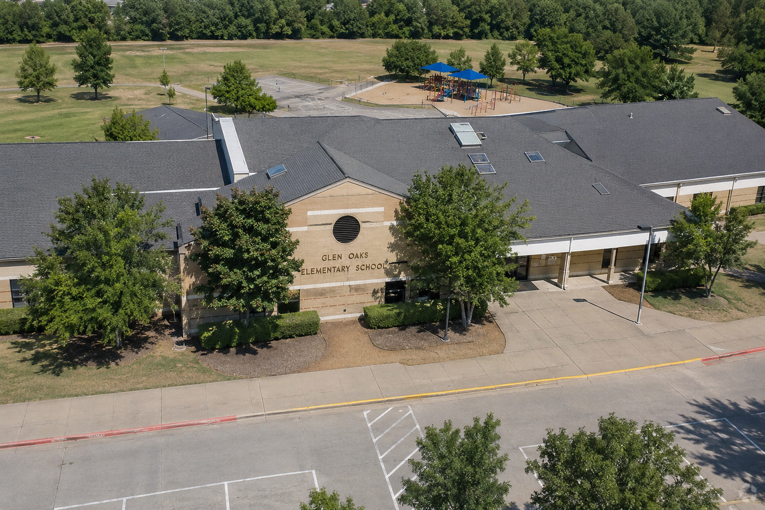 Aerial view of Glen Oaks Elementary School in McKinney, Texas, showing the McKinney ISD school campus, main entrance, playground, green space, and surrounding area.