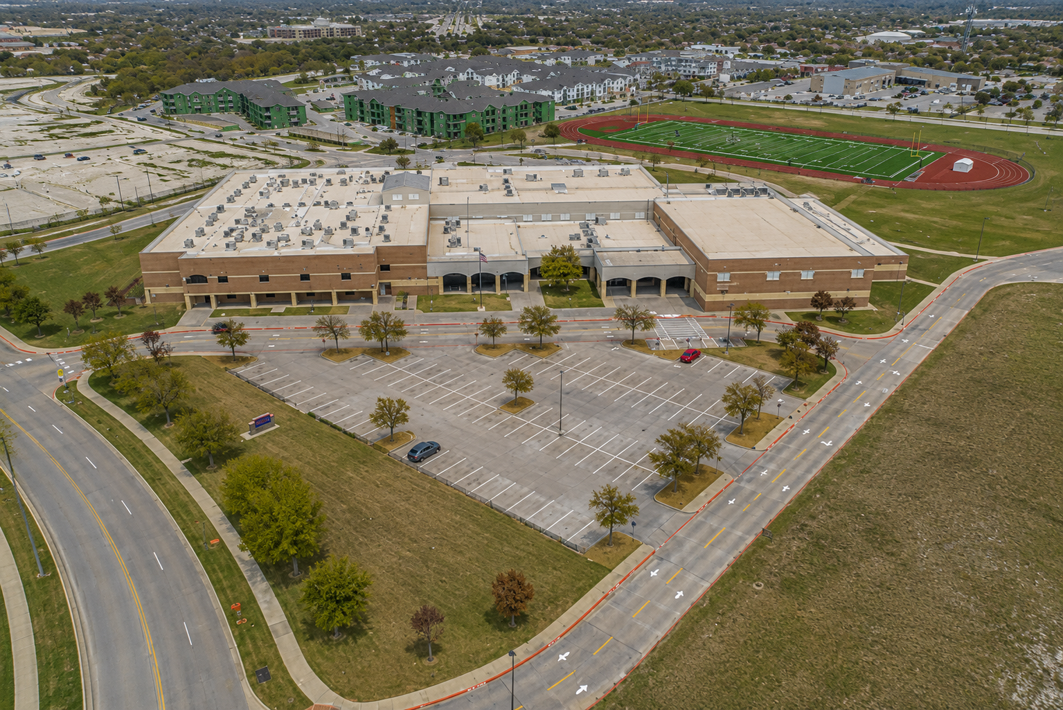 Aerial view of Scott Johnson Middle School in McKinney, Texas, showing the McKinney ISD campus, football field and track, parking areas, and surrounding residential development.