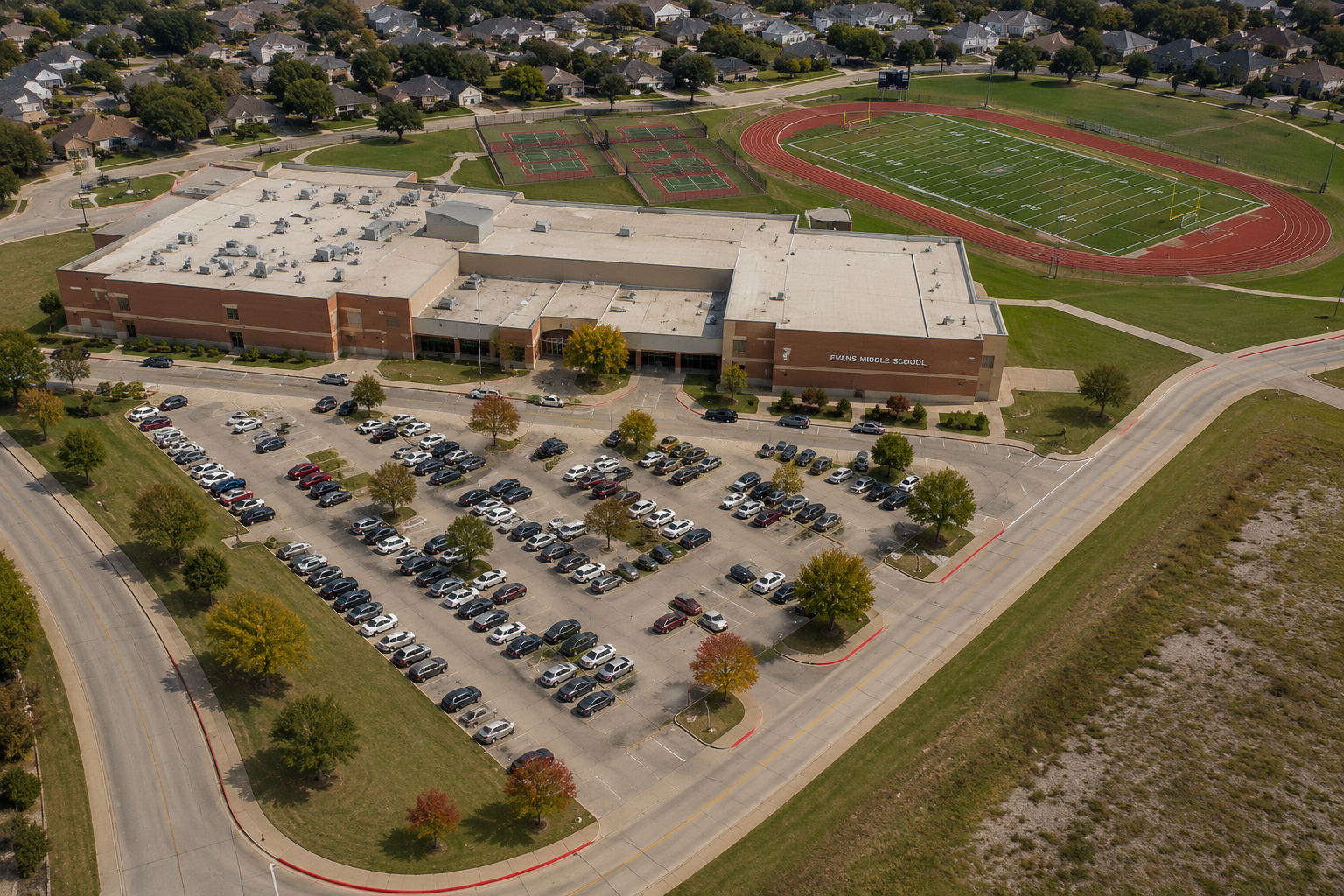 Aerial view of Evans Middle School in McKinney, Texas, showing the McKinney ISD campus, football field and track, tennis courts, parking areas, and surrounding residential neighborhoods.