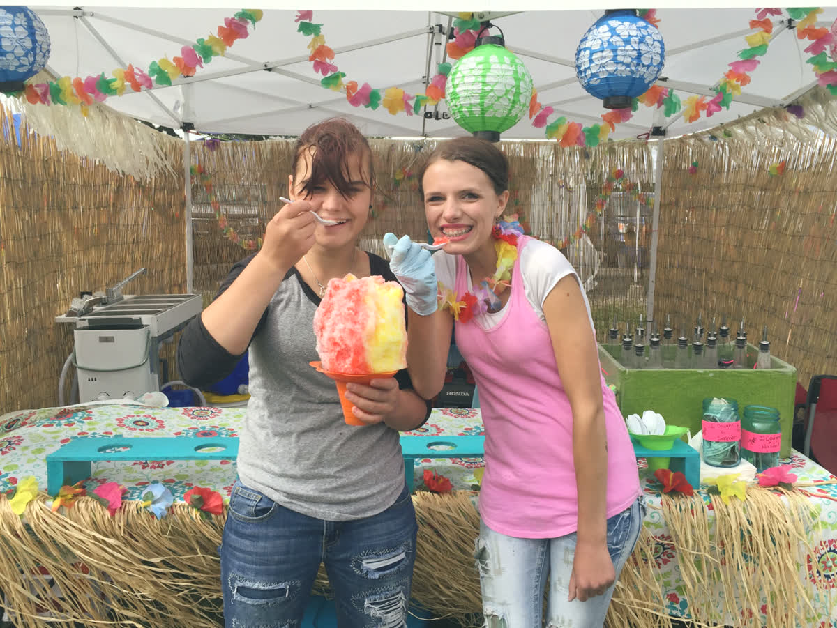 Amy&rsquo;s girls holding up rainbow shaved ice in front of the stand, Alaska 2016