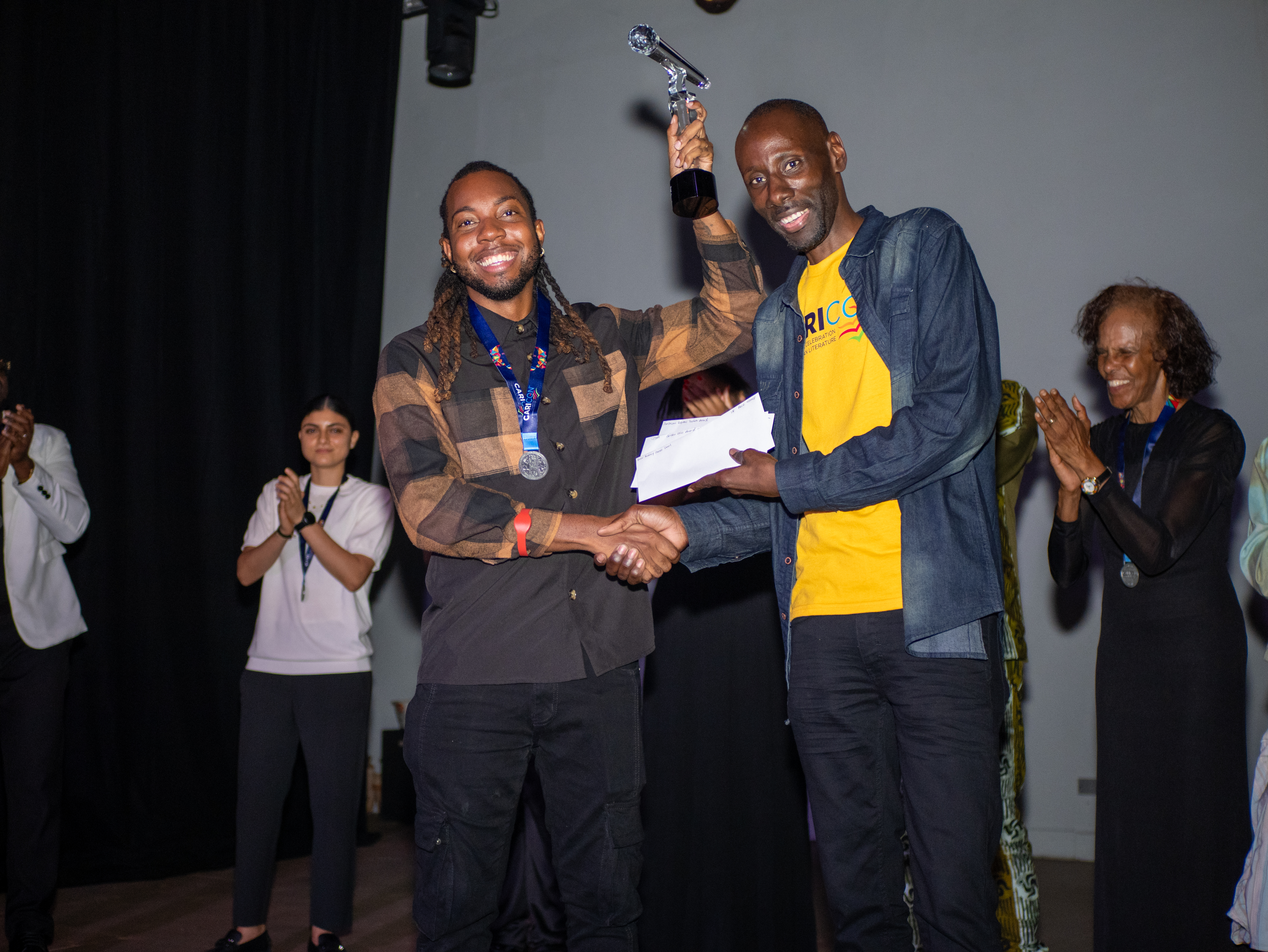 Reigning champion Akeem Chandler-Prescod receives the CARICON Poetry Slam trophy in Willemstad, 2026