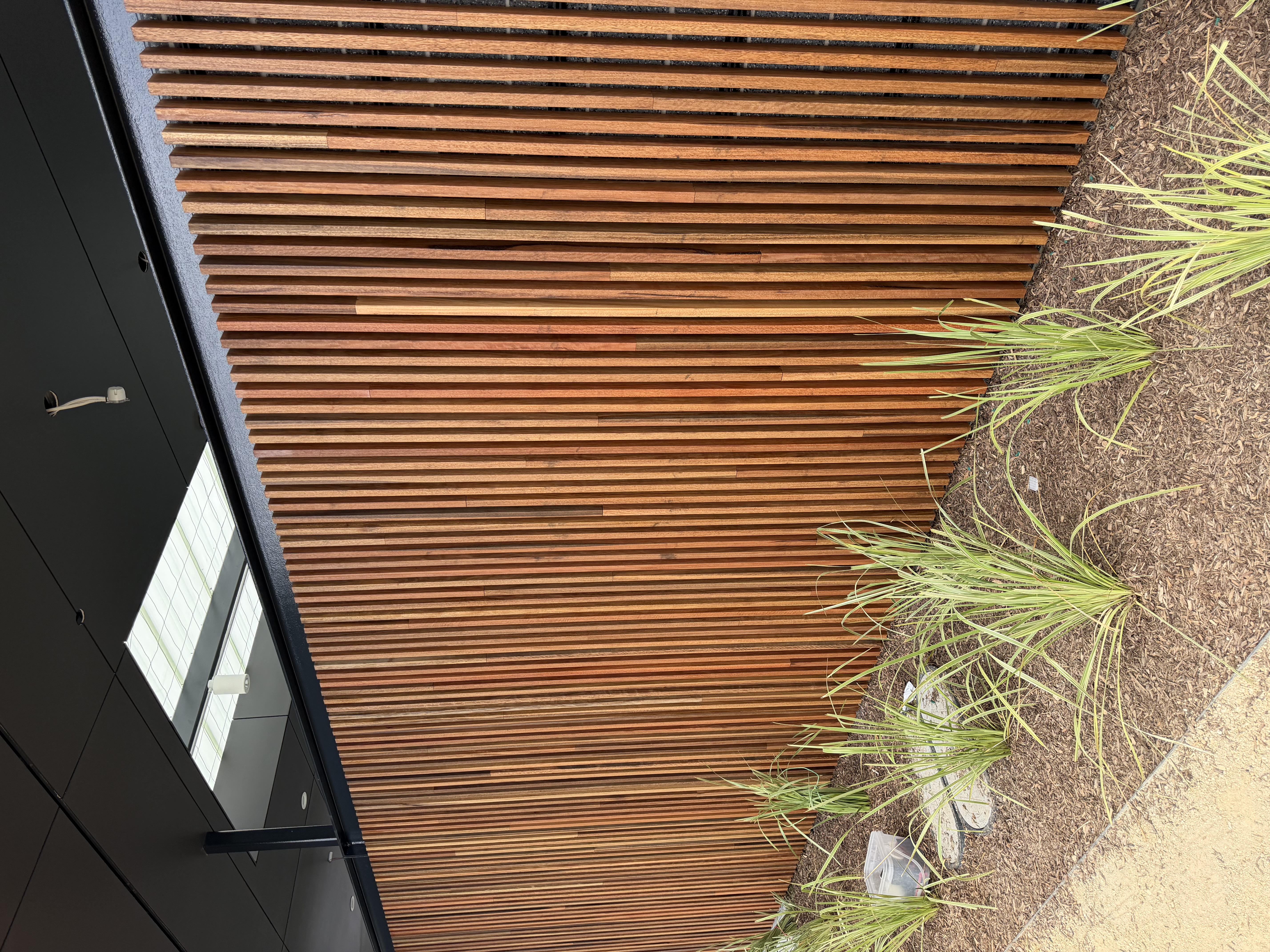 Vertical hardwood batten screen along a covered walkway