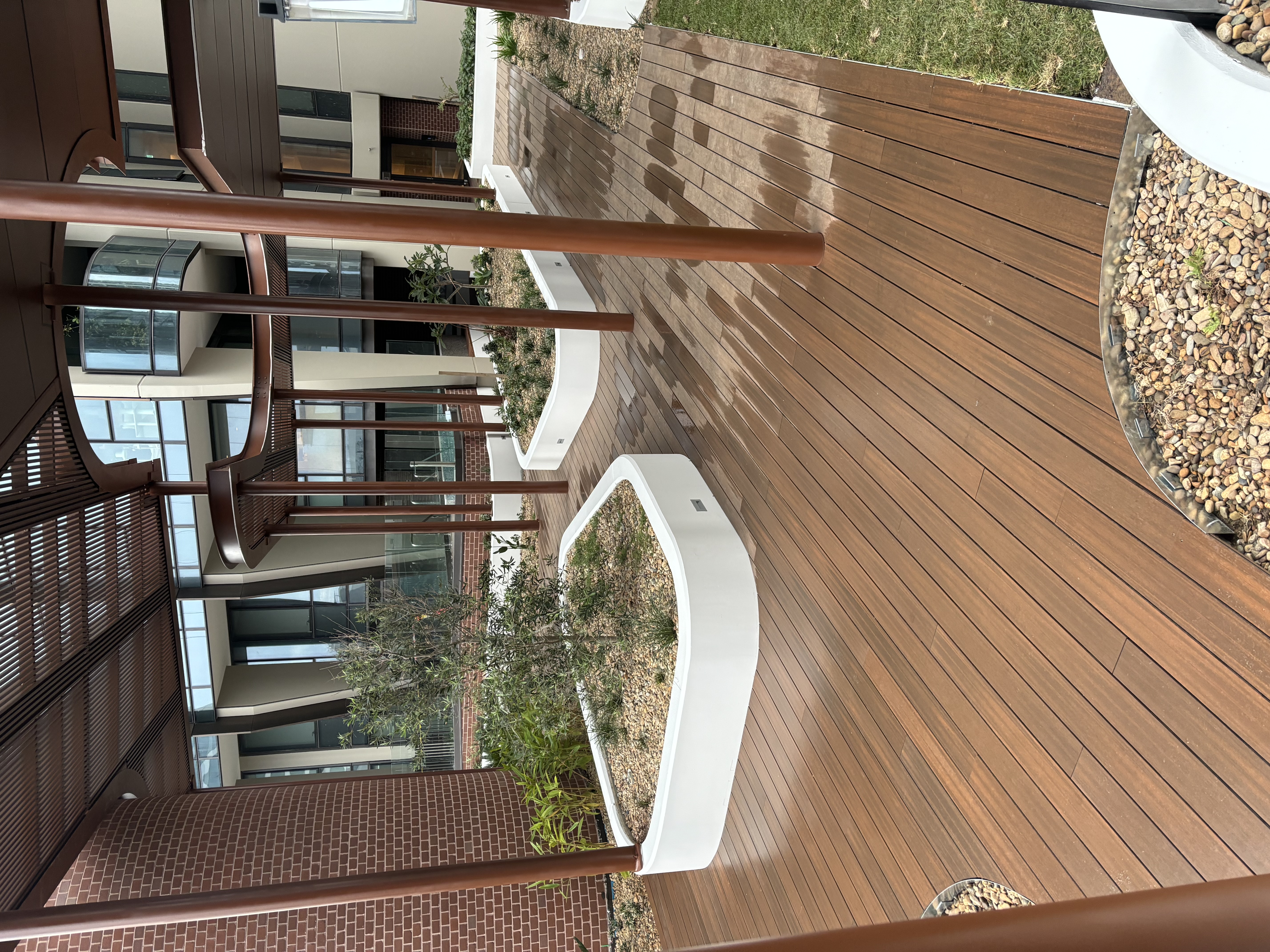 Hardwood courtyard deck with timber posts and curved planter beds