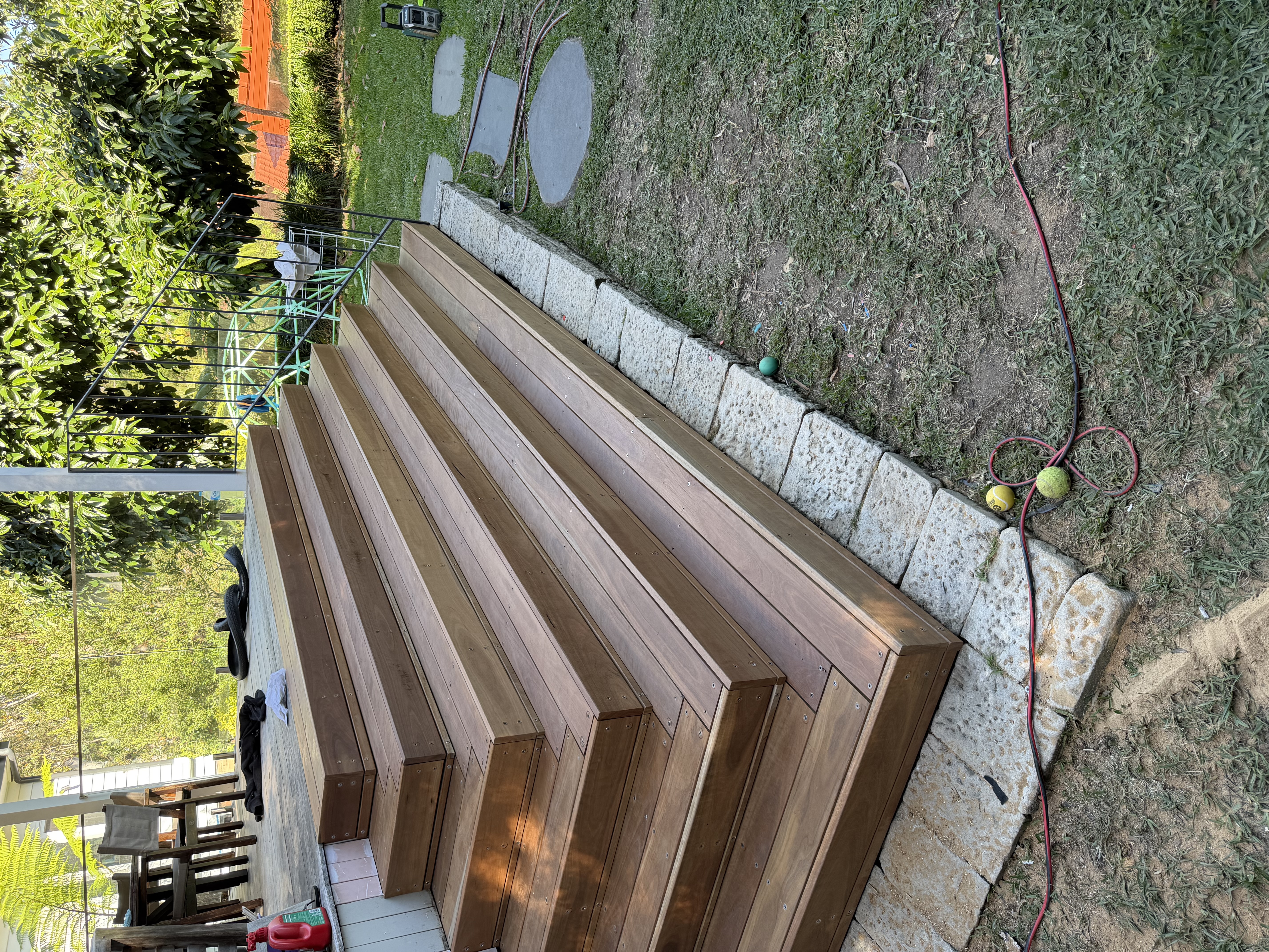 Wide hardwood stairs leading from a raised deck to the garden