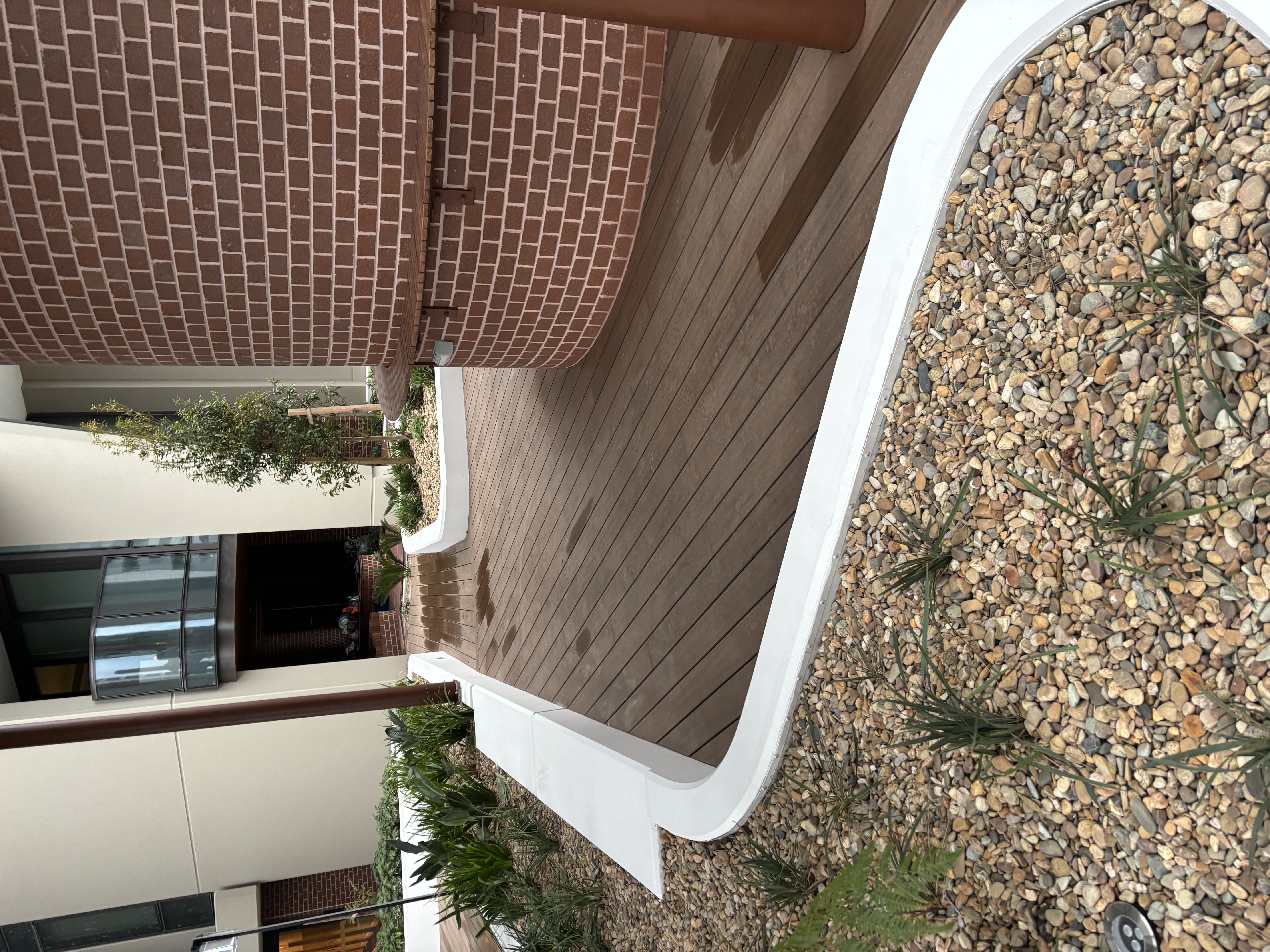 Hardwood deck curving around a brick column and white planter