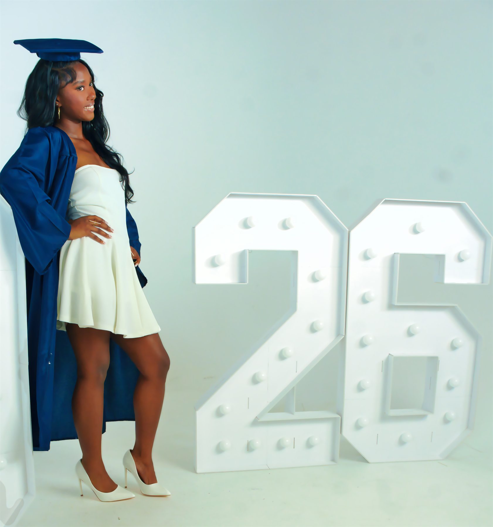 Graduate posing with 2026 celebration display