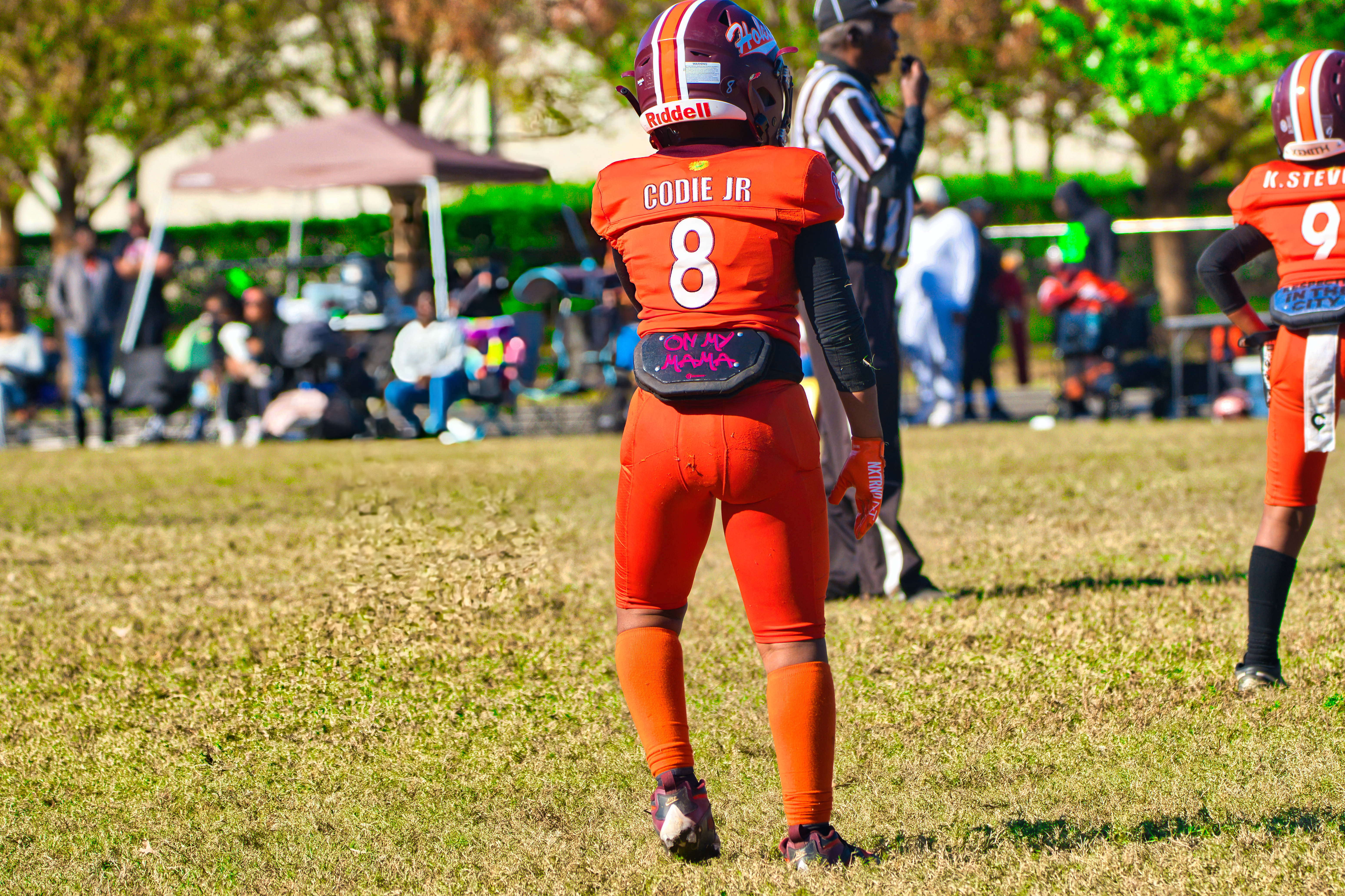 Quarterback dropping back to pass with defenders closing in during youth football game