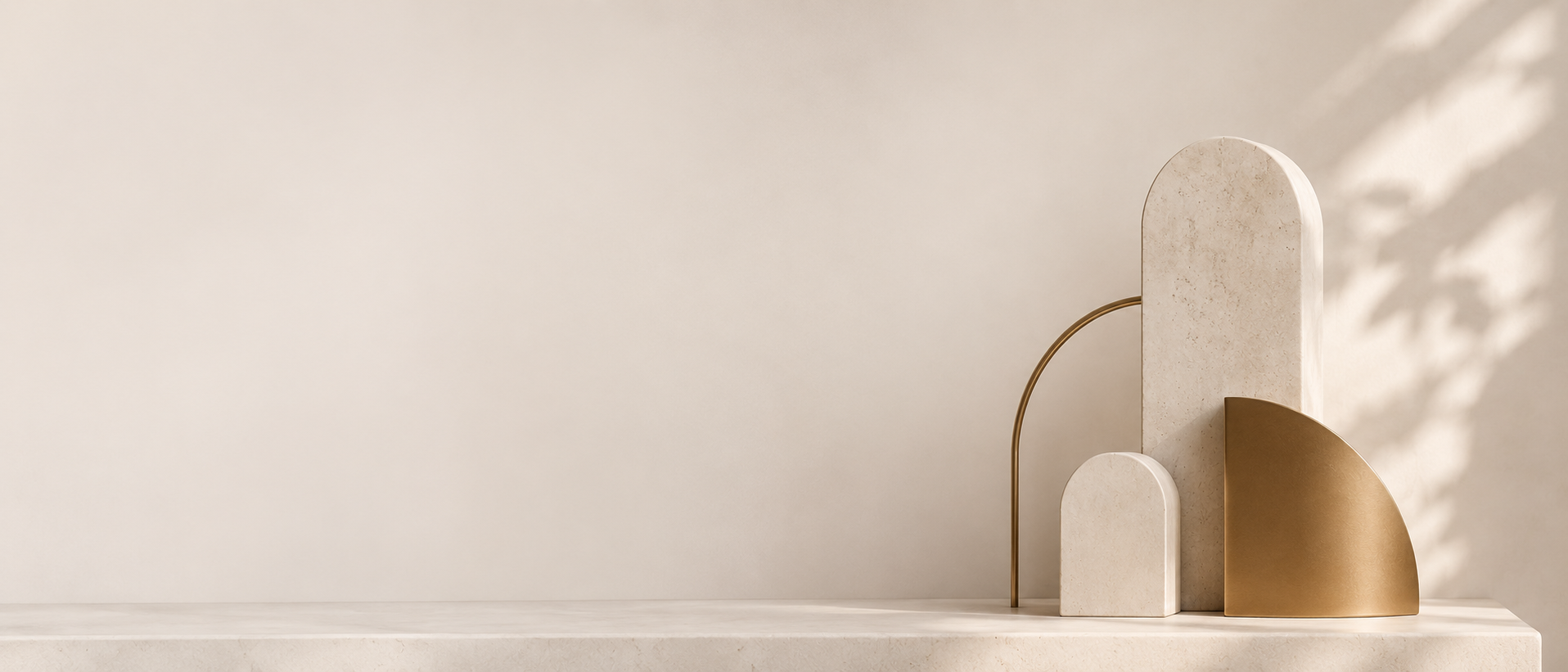 Minimal sculptural stone and brass forms on a soft ivory background.