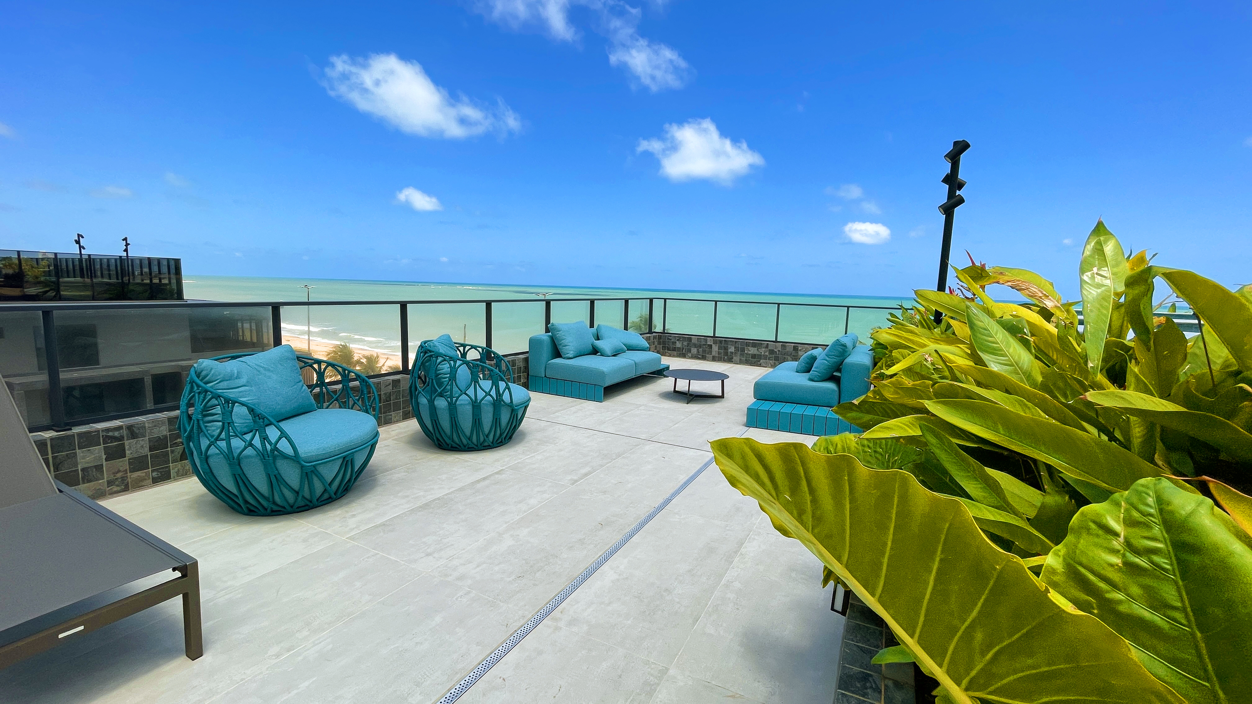 Rooftop com sofás turquesa frente mar