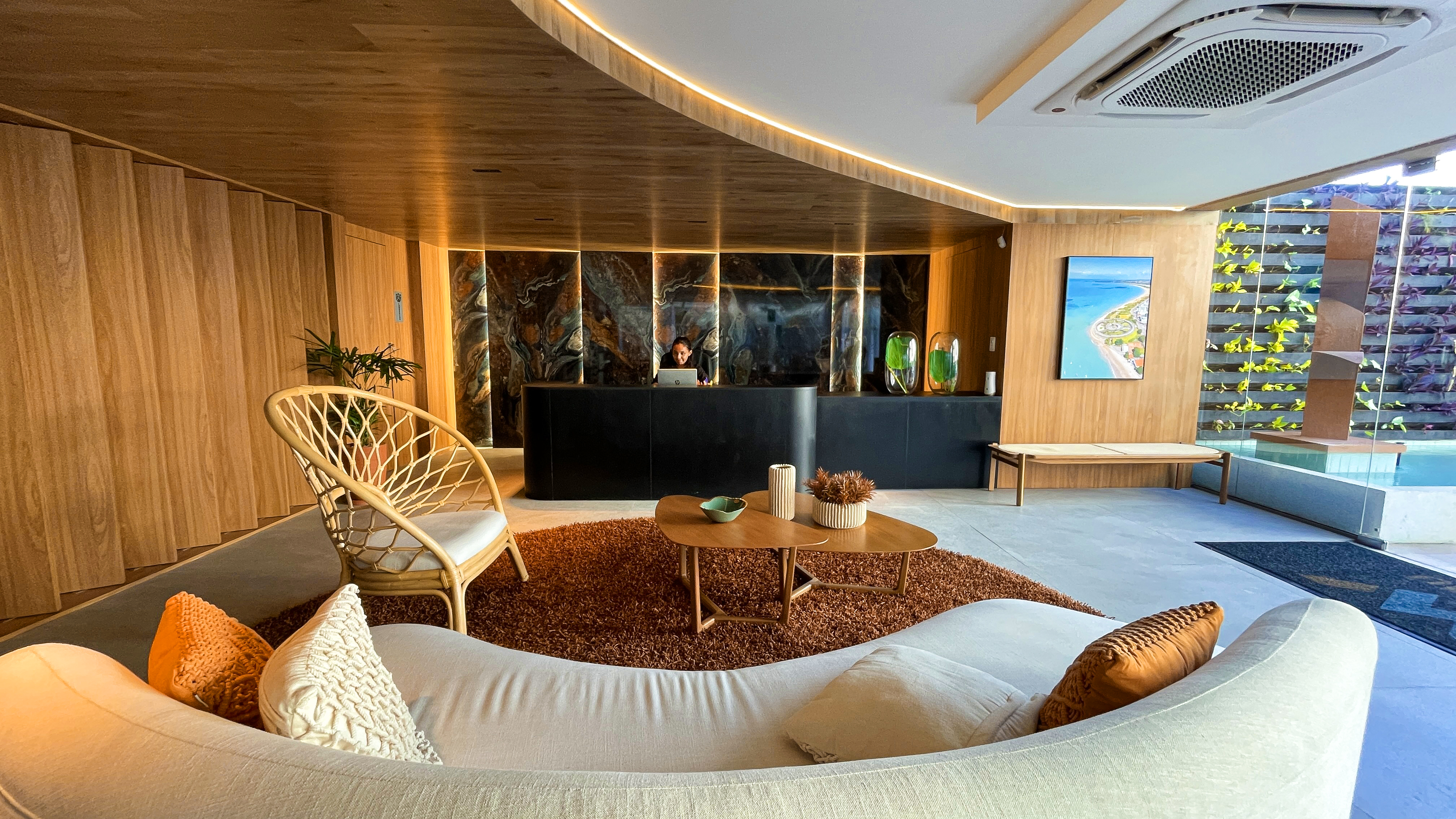 Lobby do W Tambaú com sofá curvo e recepção em mármore retroiluminado