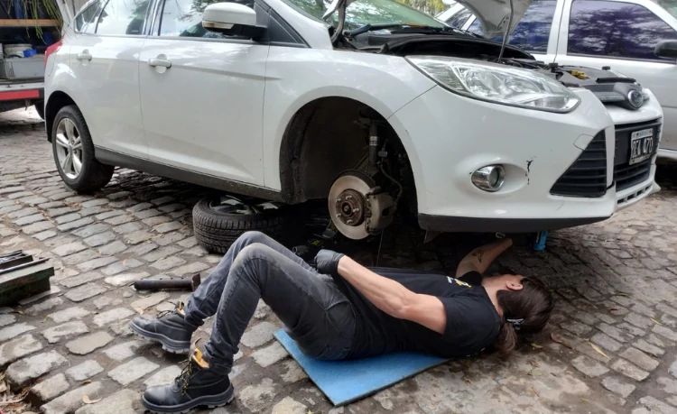 Detalle de una mano técnica revisando componentes del aire acondicionado de un vehículo