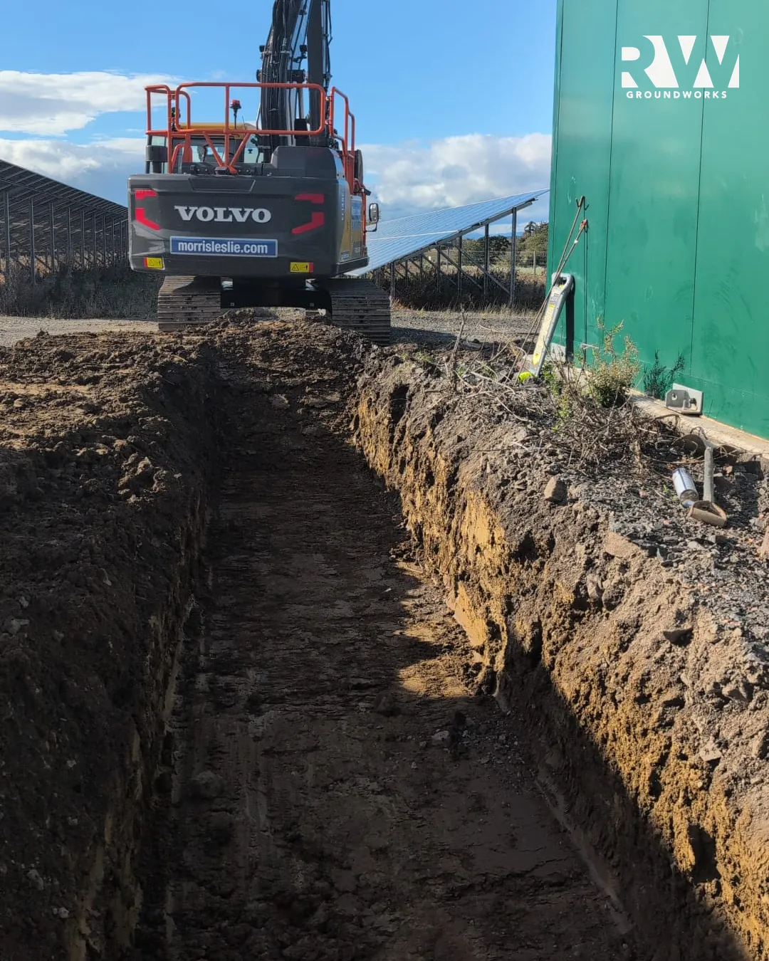 Volvo excavator digging a deep drainage trench on the solar farm