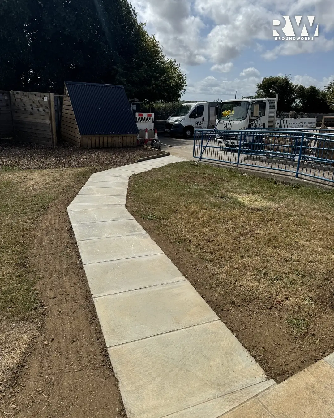 New concrete path curving to the playground railings at Gwinear Community Primary School