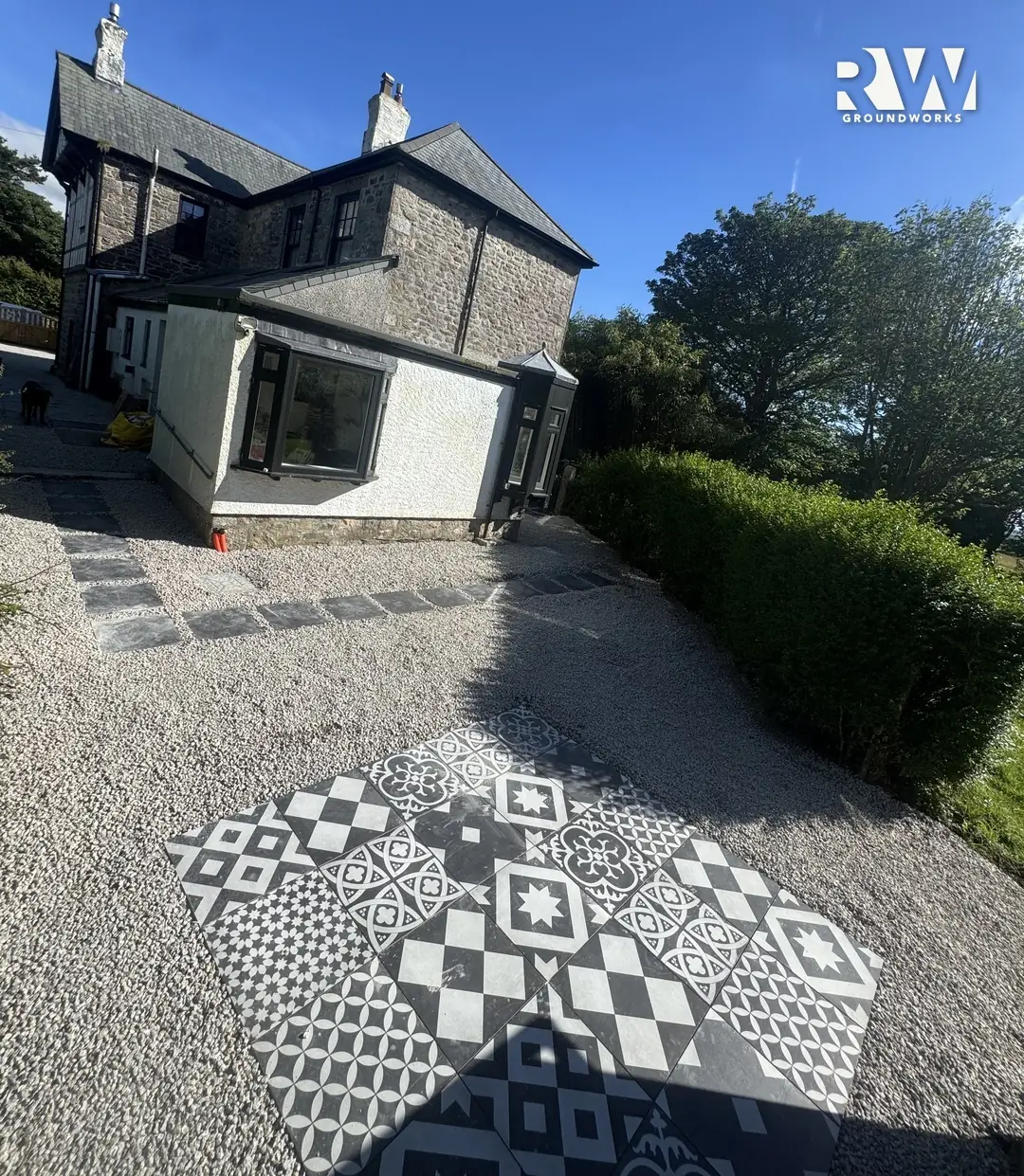 Wendron rear garden after: patterned black and white tile patio set in new gravel by RW Groundworks