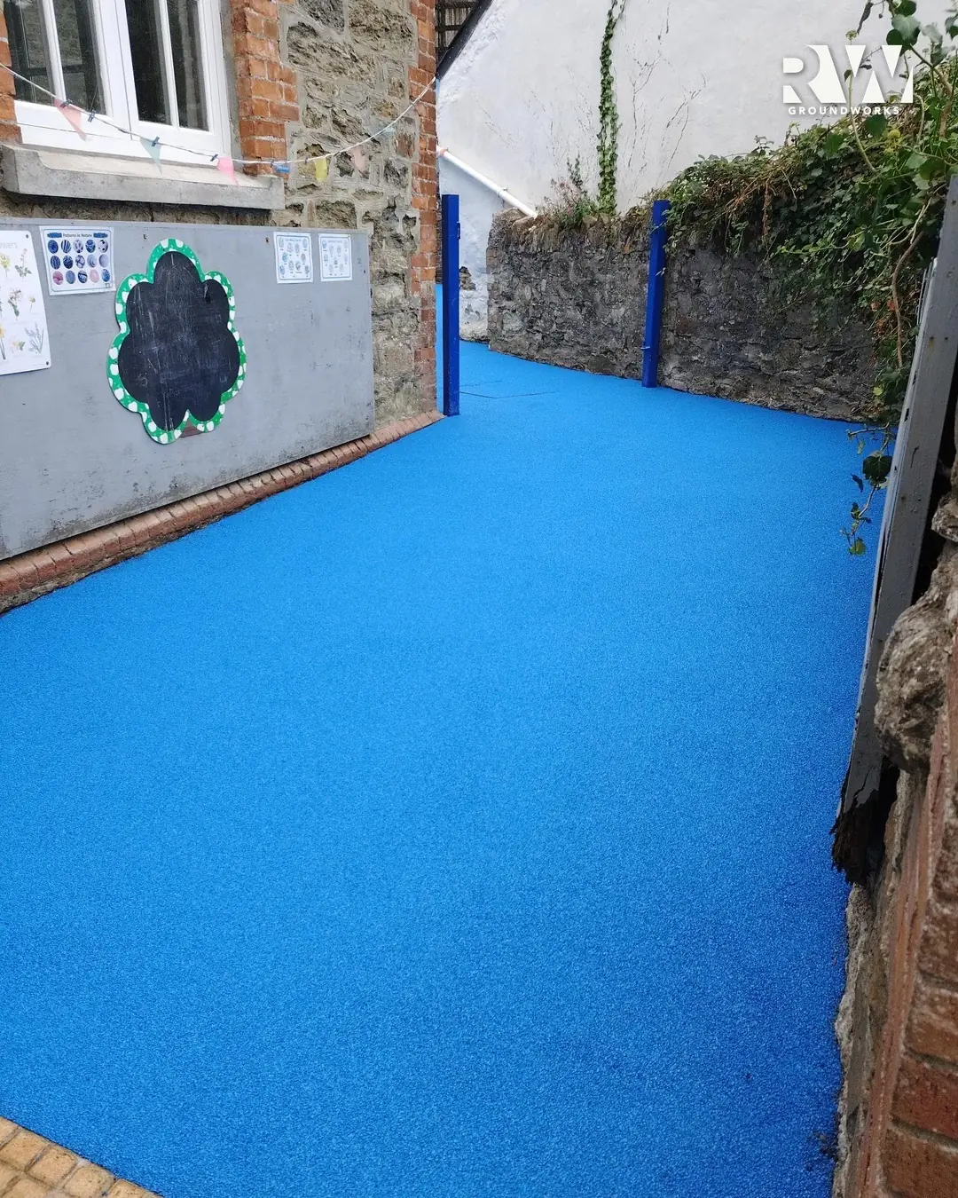 New blue wet-pour laid through the side passage at Flushing School