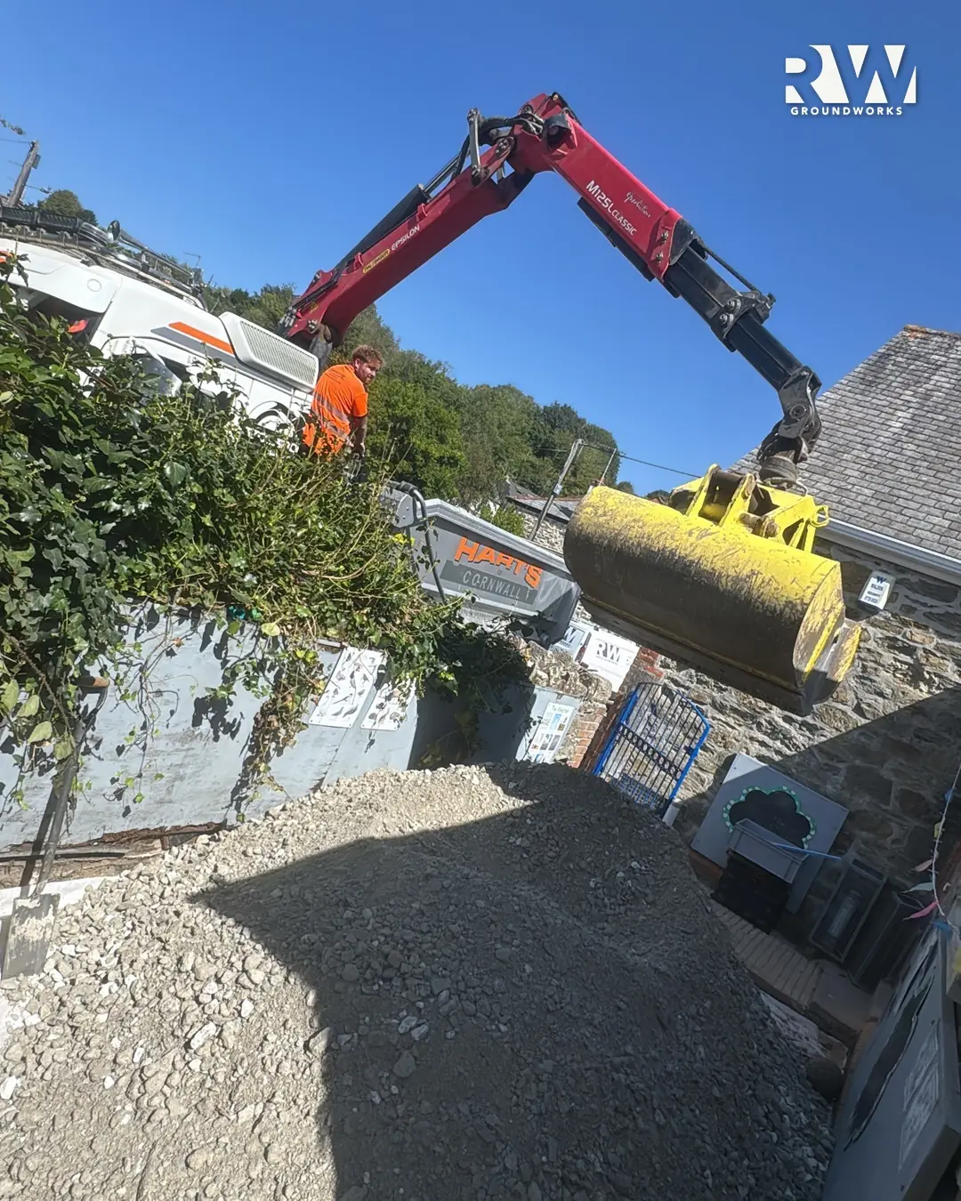 Crane lorry lifting crushed stone over the boundary wall into the Flushing School playground