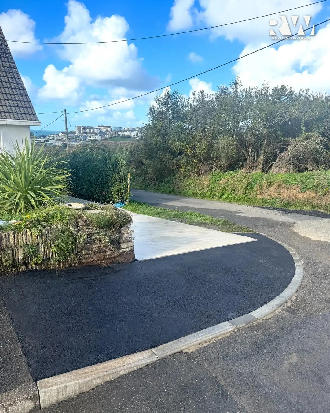 Completed dropped kerb in Newquay seen from the road, new radius kerbs round a fresh tarmac apron
