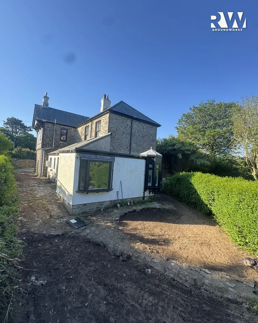 Rear garden graded to bare earth beside the hedge in Wendron