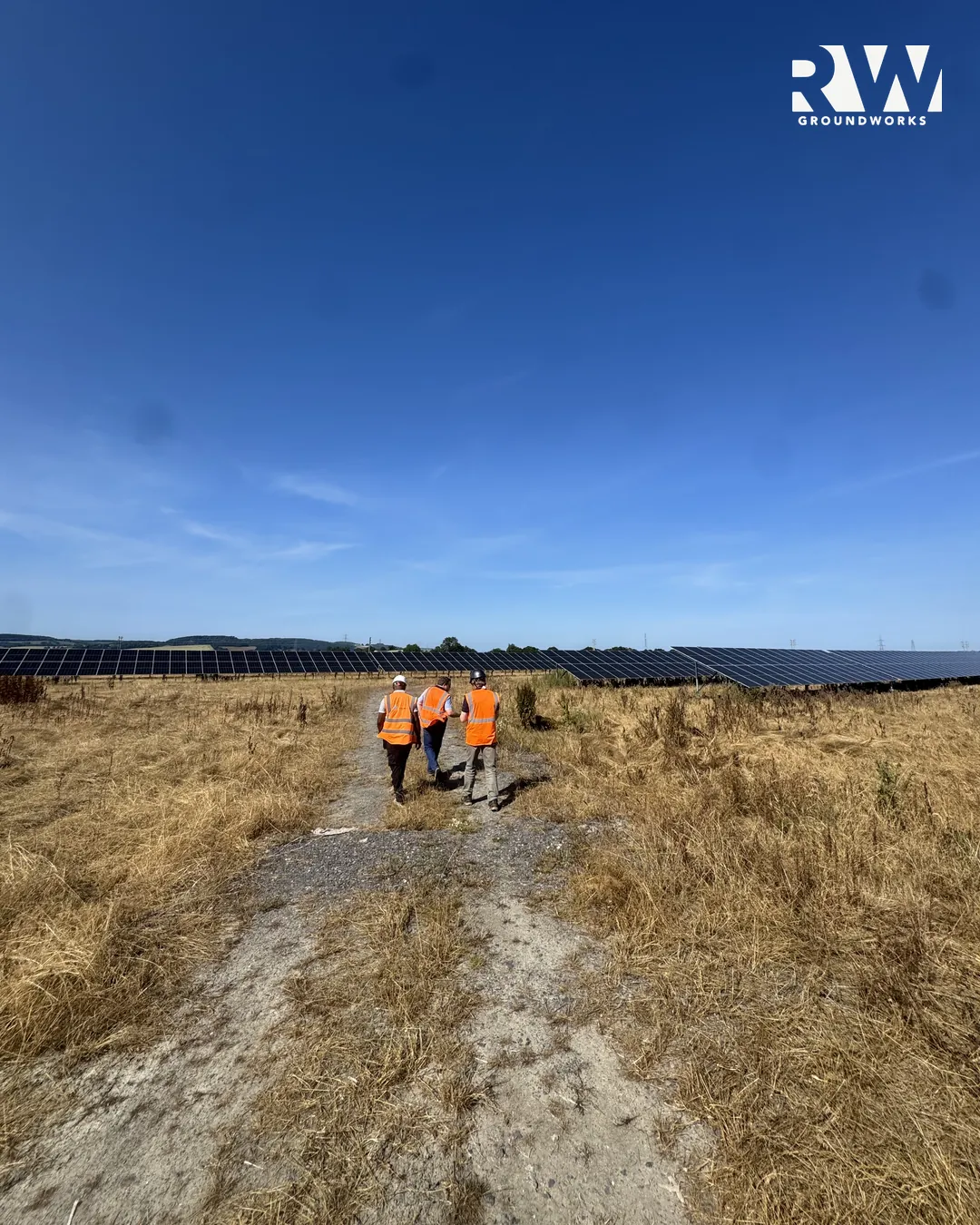 Site team in hi-vis walking the haul road between the panels