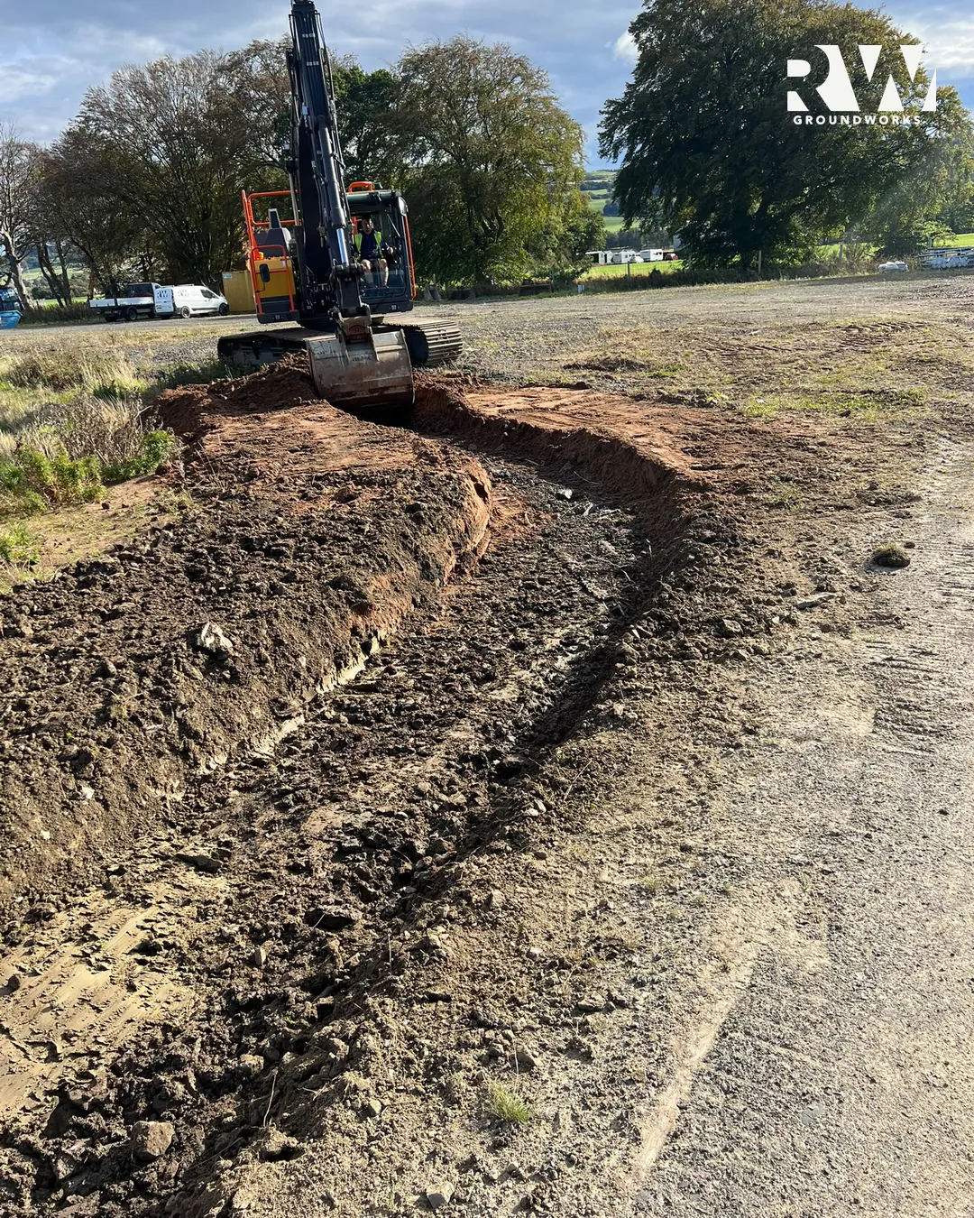 Excavator cutting a drainage run across the site