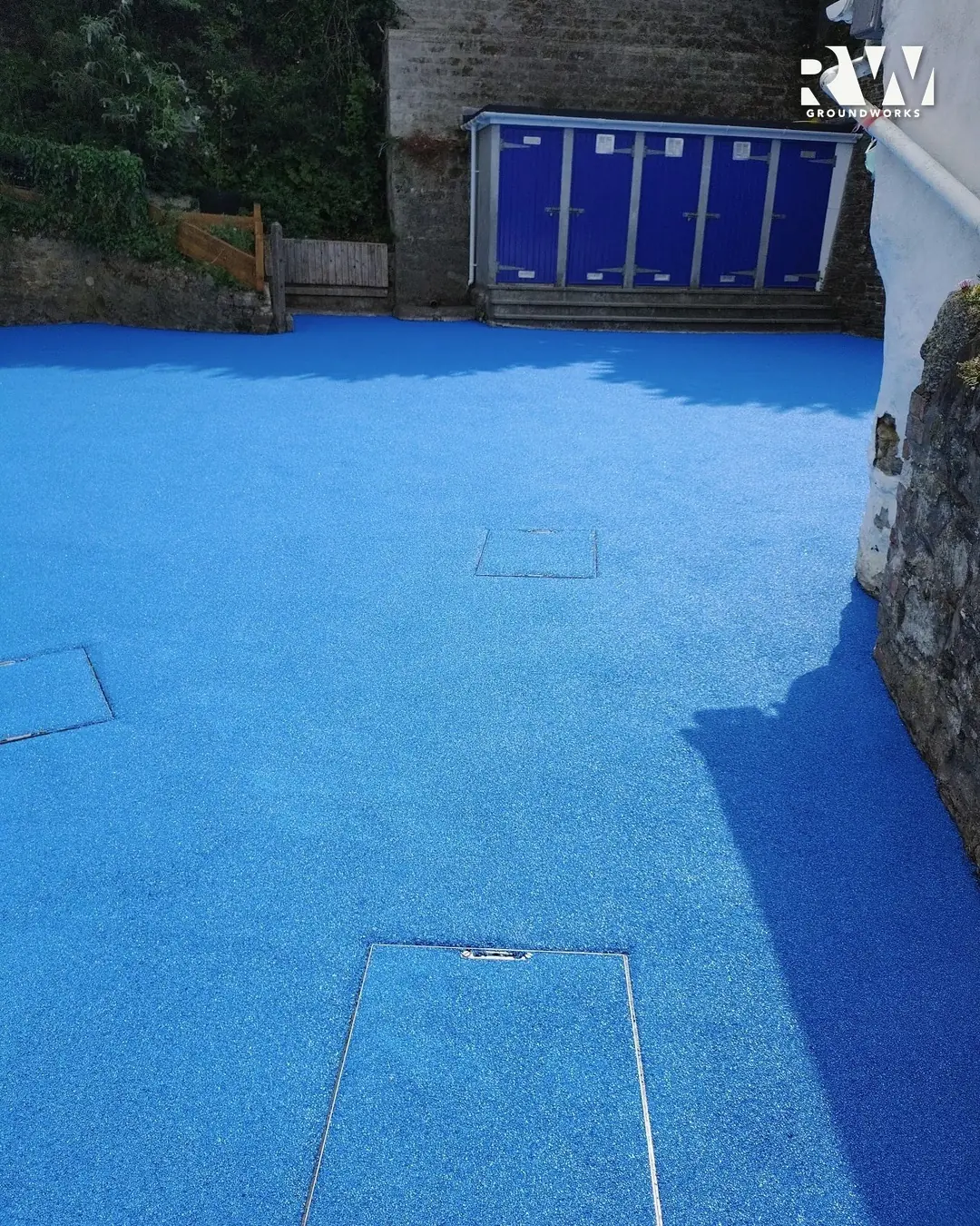 Drain covers set flush in the new blue wet-pour at Flushing School