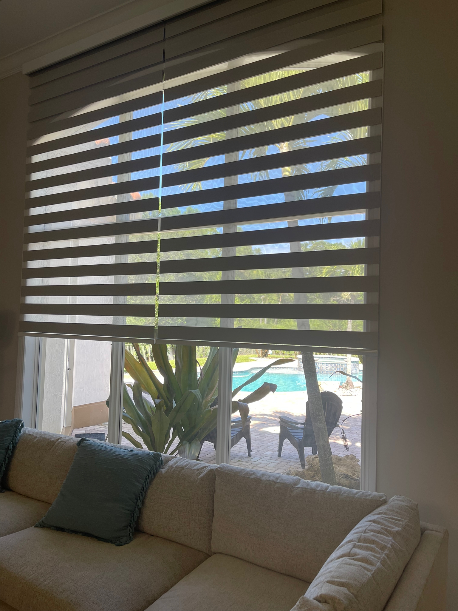 Zebra shade over a sofa with a view of the pool