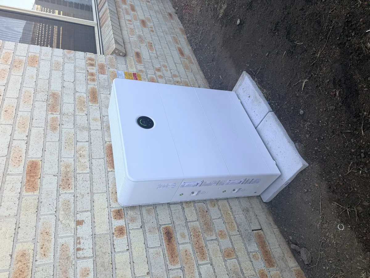 Home battery by Dunamis Power on its wall-mount bracket, ready to be fixed to a brick wall
