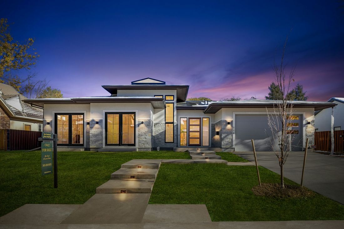 Glass-walled modern home with an infinity pool at dusk