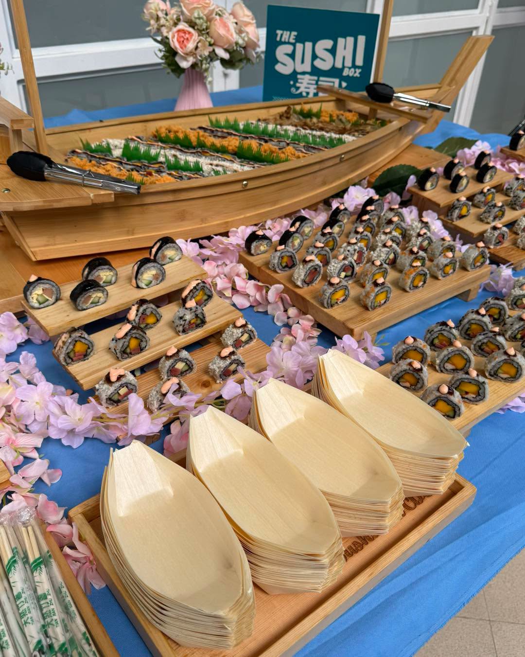 Sushi boat display with maki trays and fresh flowers