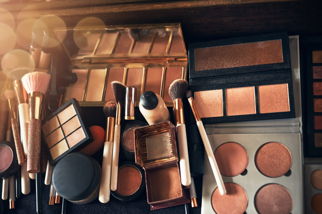 An array of professional cosmetic palettes, makeup brushes, powders, and vanity tools arranged for a custom portrait session.
