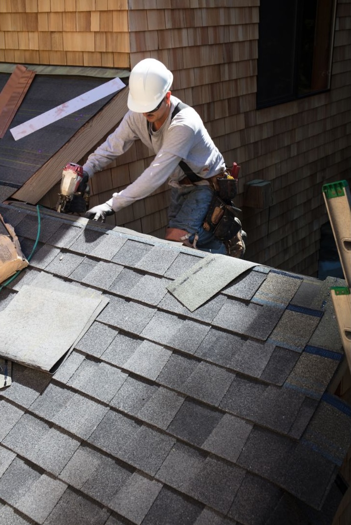 Roofer repairing shingles on a roof