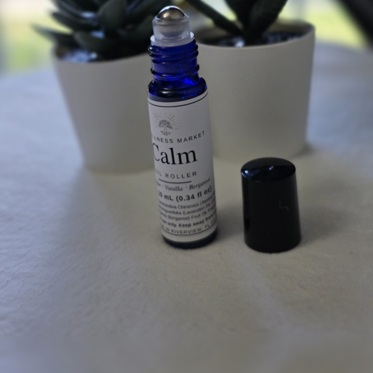 Calm oil roller in a blue glass bottle with succulents and potted plants