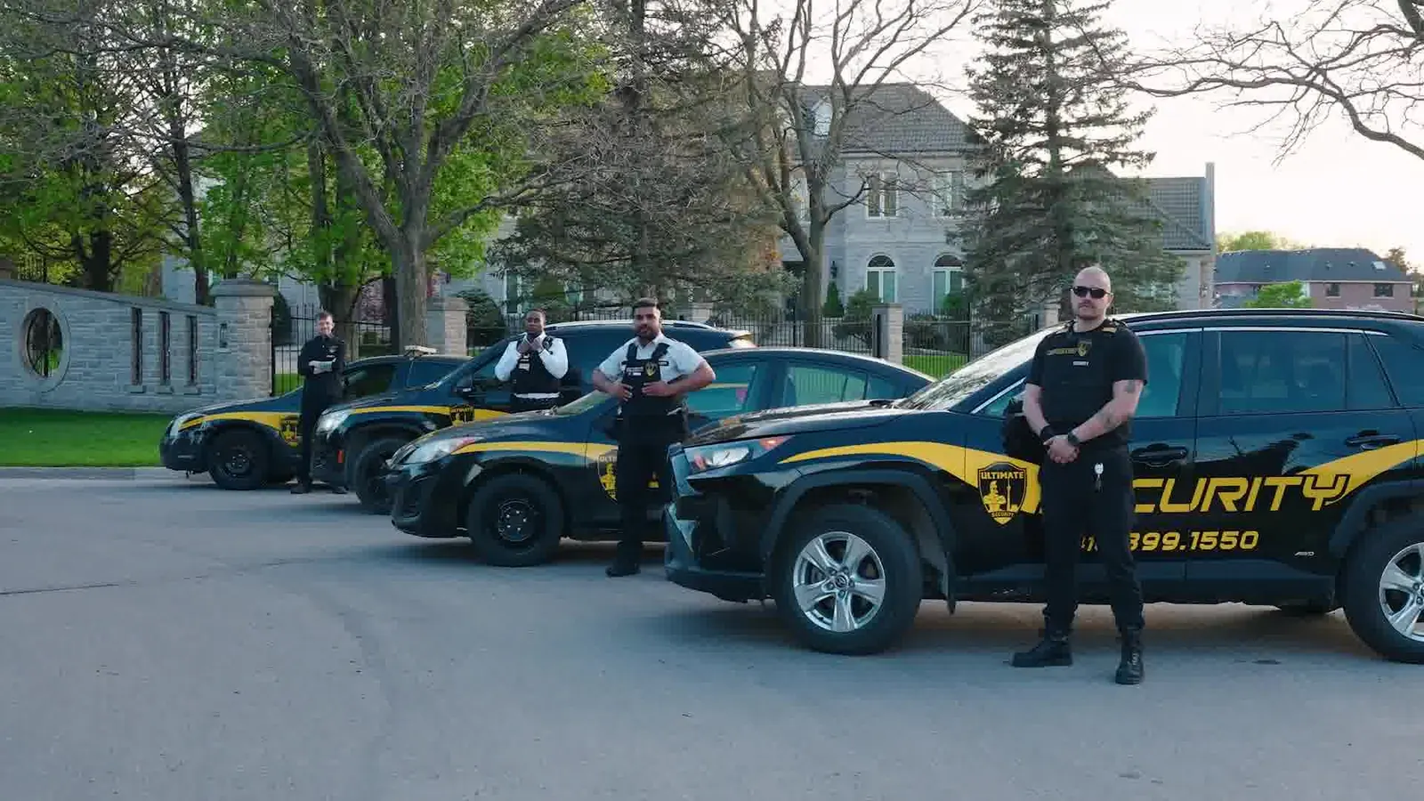 Three Ultimate Security patrol vehicles and an officer on a residential street